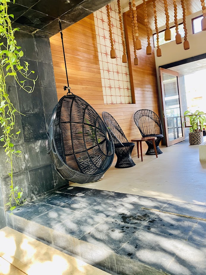 Hotel lobby with a hanging rattan chair and warm wood walls